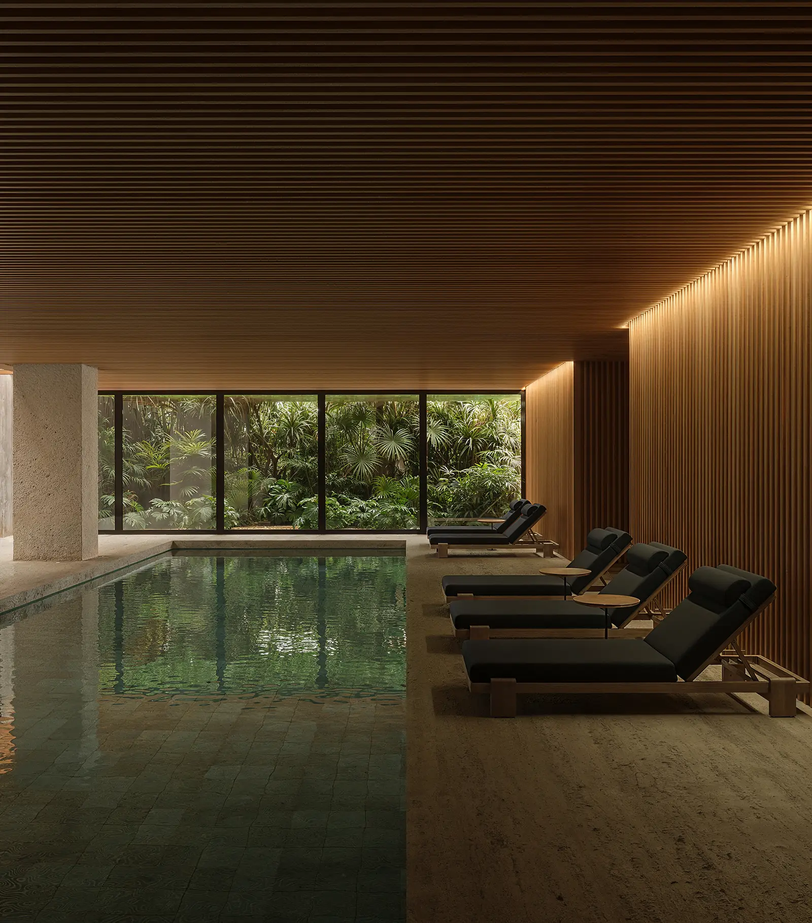 Indoor swimming pool with timber ceiling, loungers and garden view